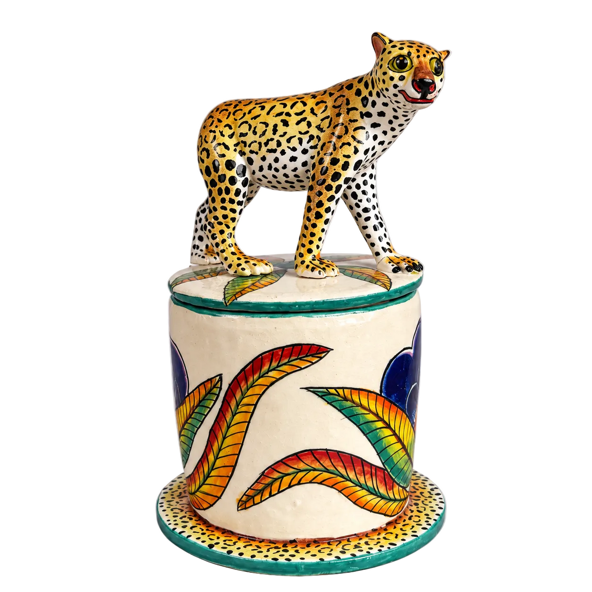 A hand-painted ceramic figurine of a leopard standing on top of a decorated cylindrical pedestal, set against a plain light gray background.