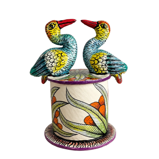 A hand-painted ceramic sculpture of two birds perched on top of a cylindrical pot with a matching base, set against a plain light gray background.