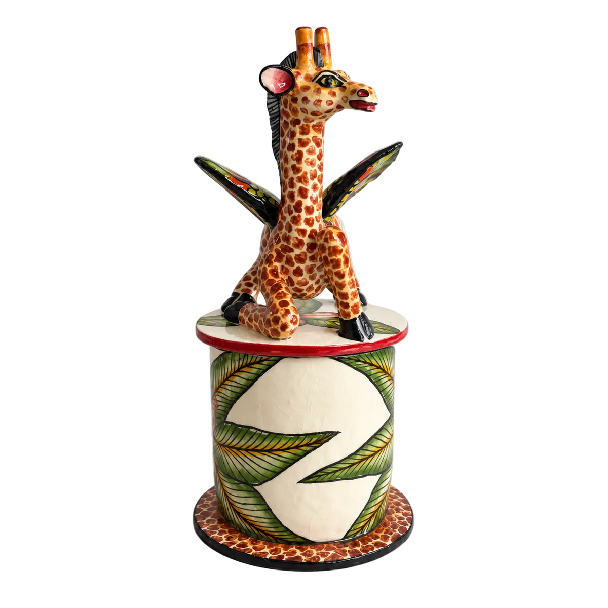 A hand-painted African ceramic giraffe figurine standing on a decorated cylindrical pedestal base, photographed against a neutral light gray background.