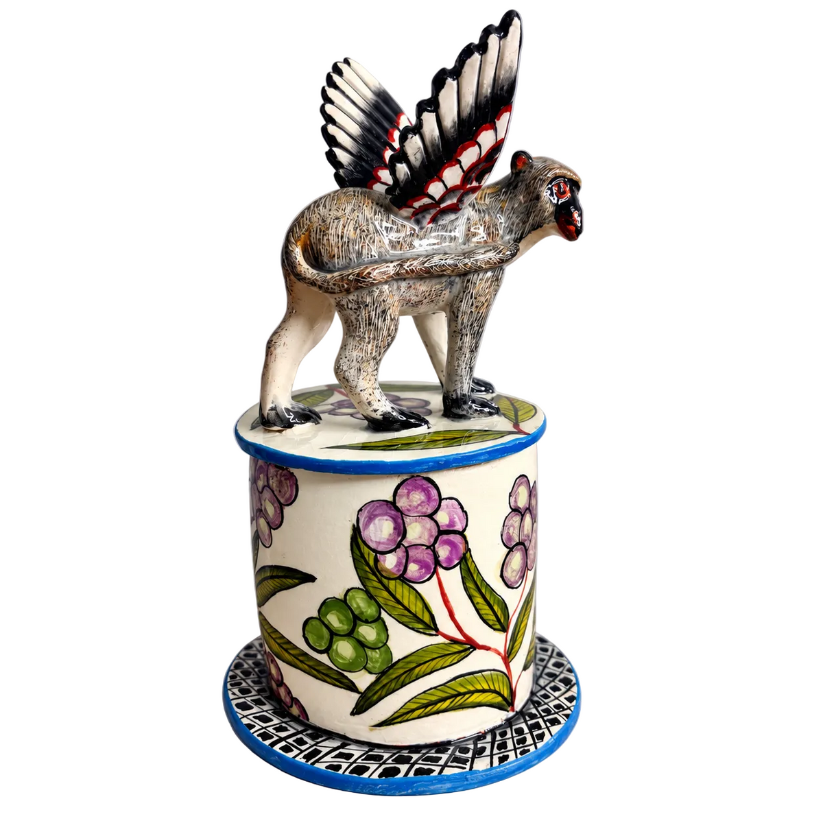 A decorative ceramic figurine of a winged monkey on top of a cylindrical pot with a floral pattern, set against a neutral gray background.