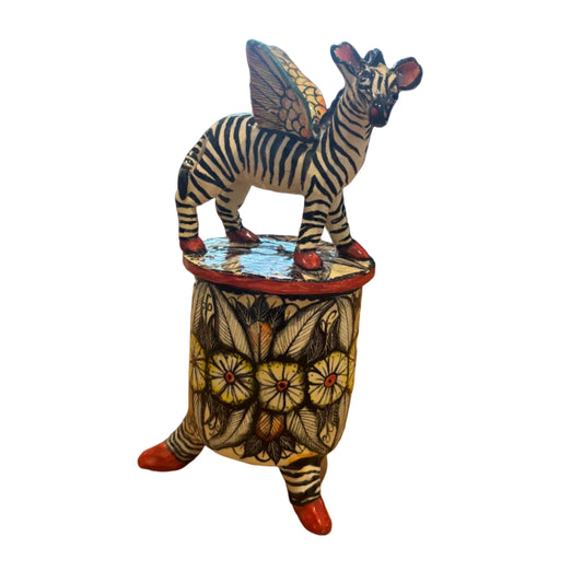 A hand-painted zebra figurine atop a lid of a trinket container. Ceramic art.  