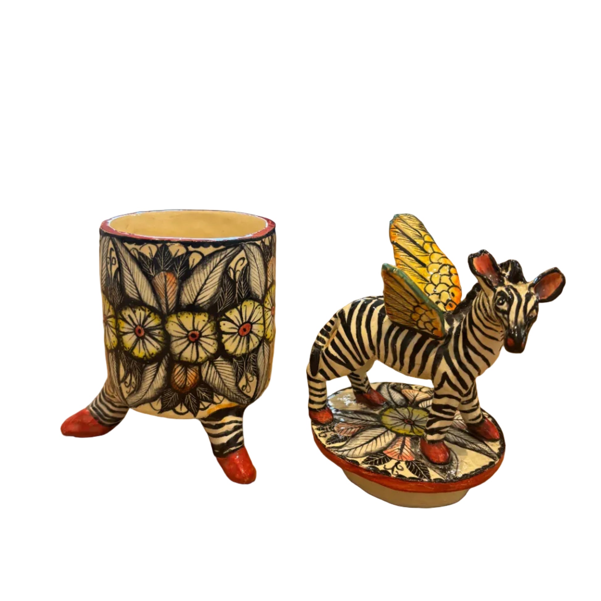 A hand-painted ceramic zebra figurine with wings on top of a lid and a matching pot.  